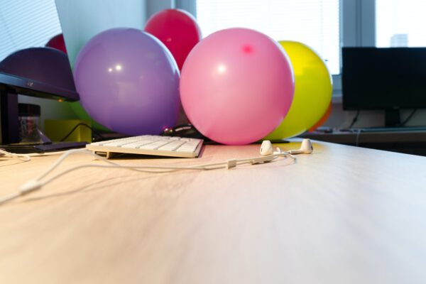 Kilka kolorowych balonó reklamowych leży na biurku w biurze przy komputerze
