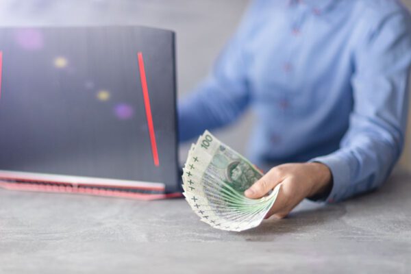 Mężczyzna przed laptopem trzyma pieniądze w ręce